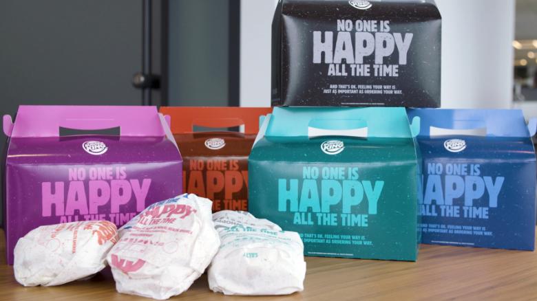 Photo of Burger King's 'Unhappy Meals' boxes with three packaged burgers sitting next to them. 