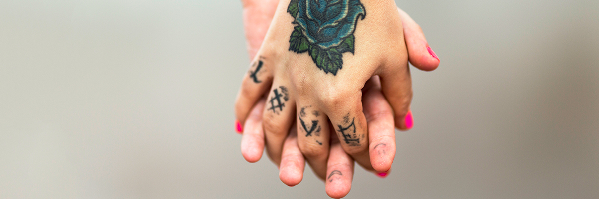 Two tattooed hands entangled