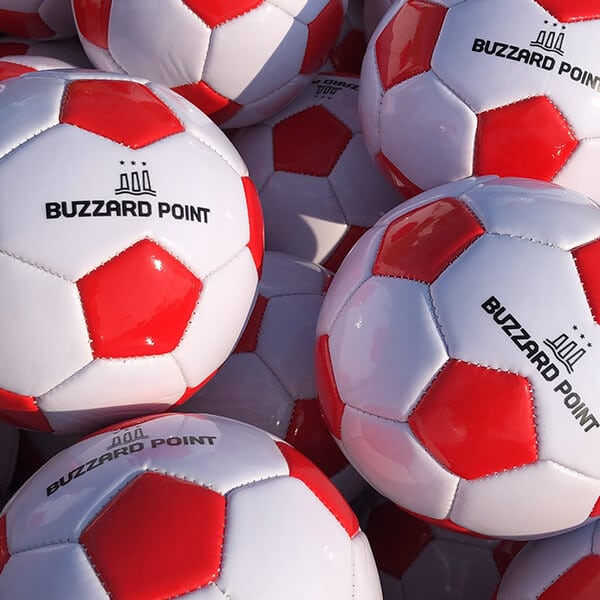 White and red soccer balls with Buzzard Point logo on them