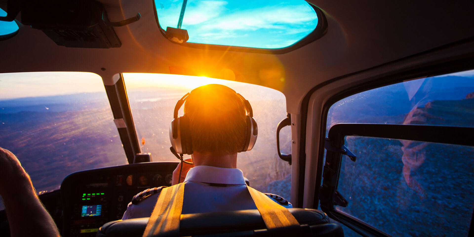 pilot flying a plane looking at the view with a sunset
