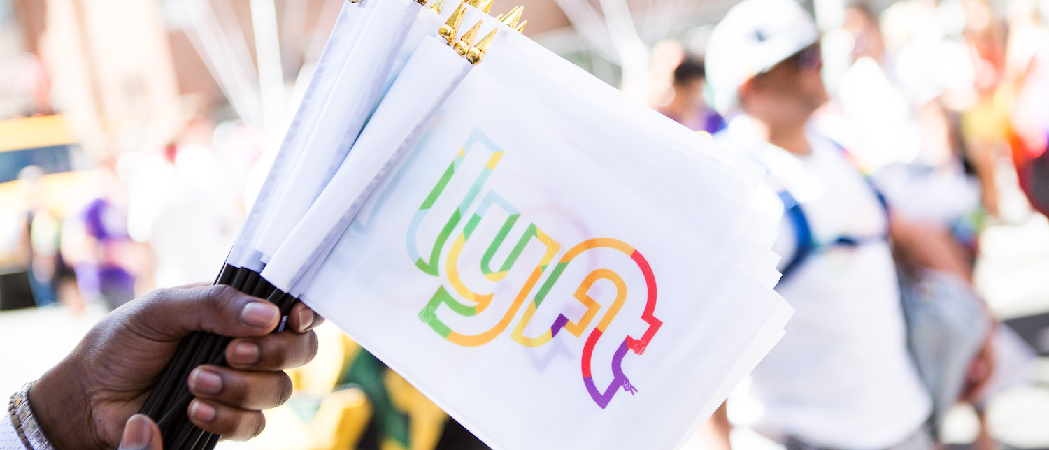 Photo of person's hand holding Lyft branded Pride flags. 